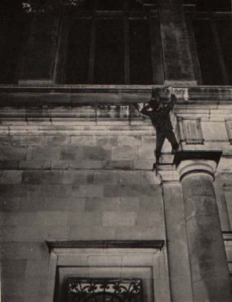 The climber starts up the window shown in the bottom of the picture. Balancing on the ledge above the window, he reaches for the column and pulls up to his present position. He then mantelshelves over the overhang. (Notice the climber's arched back.)